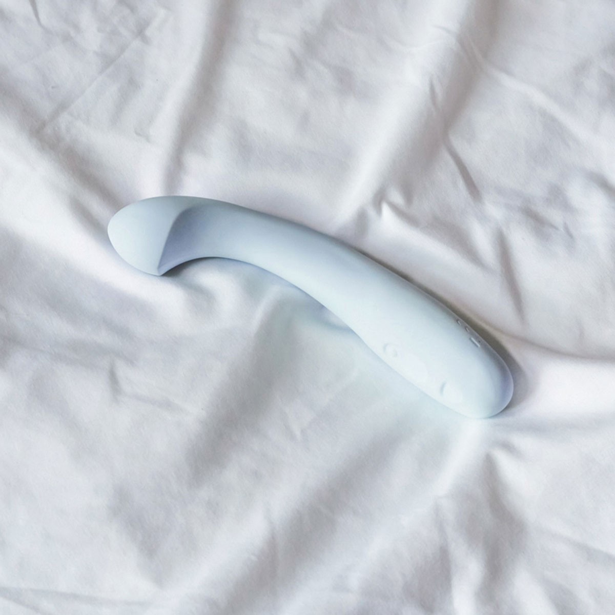 Lifestyle shot featuring the  Dame Products vibrator beside the bed